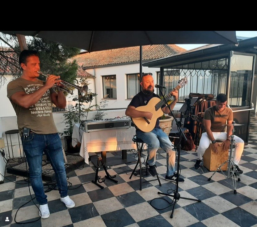 Actuación de grupo musical en un evento privado de Madrid, músicos tocando guitarra y cajón en un ambiente cercano y alegre.
